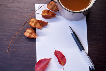 Autumn foliage pen and paper on the table.