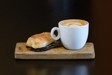 cup of coffee with a bun on a wooden stand
