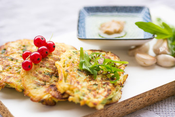 Vegetable zucchini pancakes, served with fresh herbs and garlic yogurt sauce, vegetarian  fritters 