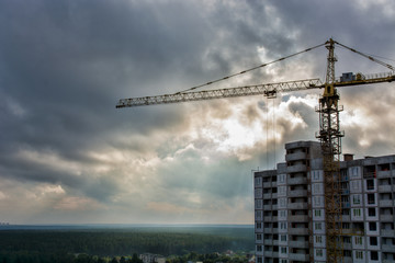 Fototapeta premium Silhouette of Industrial construction cranes and building site over stormy sky. grunge filter photo 