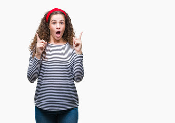 Fototapeta na wymiar Beautiful brunette curly hair young girl wearing stripes sweater over isolated background amazed and surprised looking up and pointing with fingers and raised arms.