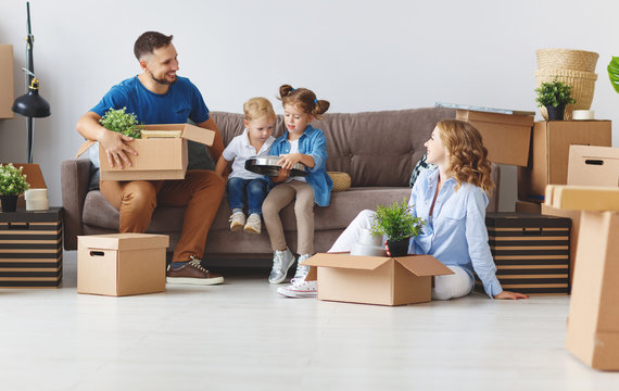 happy family mother father and children move to new apartment and unpack boxes.