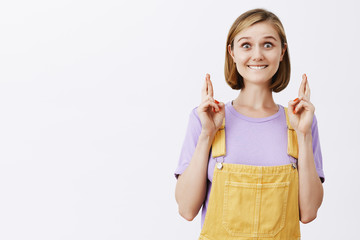 Excited and thrilled overwhelmed woman with fair hair and short hairstyle, biting lip and smiling...