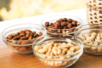 Assortment of mixed nuts and wicker basket on wood table background