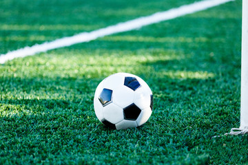 classical black and white football ball on the green grass of the field. Soccer game, training,...