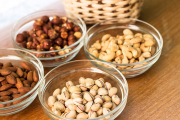 Assortment of mixed nuts and wicker basket on wood table background