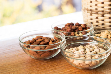 Assortment of mixed nuts and wicker basket on wood table background