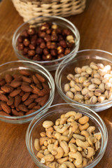 Assortment of mixed nuts and wicker basket on wood table background
