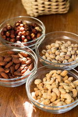 Assortment of mixed nuts and wicker basket on wood table background