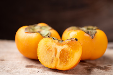 Half of persimmon fruit on wooden background