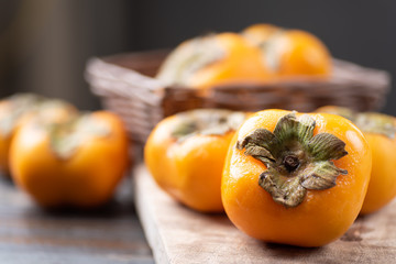 Ripe persimmon fruit in a basket on wooden background, healthy fruit