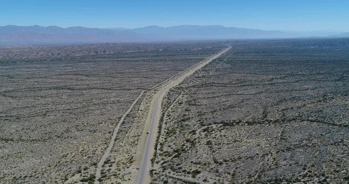 Aerial drone scene of road at wide pampa. Famatina mountains at background. Dry landscape. Rioja province, argentina