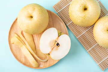 Fresh Asian pear fruit on wooden plate and bamboo sheet, top view