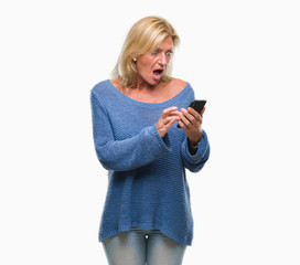 Middle age blonde woman sending message using smartphone over isolated background scared in shock with a surprise face, afraid and excited with fear expression