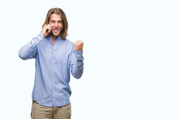 Young handsome man with long hair over isolated background talking on the phone screaming proud and celebrating victory and success very excited, cheering emotion