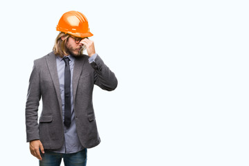 Young handsome architec man with long hair wearing safety helmet over isolated background tired rubbing nose and eyes feeling fatigue and headache. Stress and frustration concept.