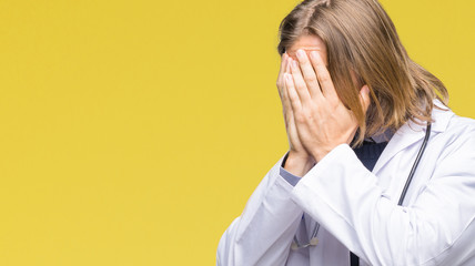 Young handsome doctor man with long hair over isolated background with sad expression covering face with hands while crying. Depression concept.