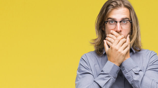 Young handsome business man with long hair over isolated background shocked covering mouth with hands for mistake. Secret concept.