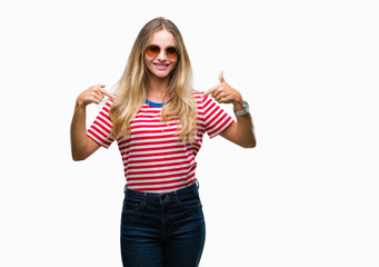 Obraz na płótnie Canvas Young beautiful blonde woman wearing sunglasses over isolated background looking confident with smile on face, pointing oneself with fingers proud and happy.