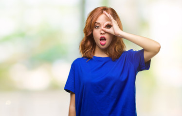 Young beautiful woman over isolated background doing ok gesture shocked with surprised face, eye looking through fingers. Unbelieving expression.