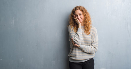 Fototapeta premium Young redhead woman over grey grunge wall thinking looking tired and bored with depression problems with crossed arms.