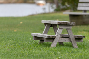 Benches and picinic tables at marina, blurred boat, blurred water in background.