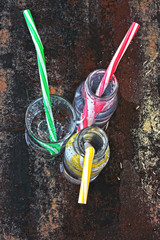 Mineral water in glass bottles and glass. Drinking bottled water with cocktail tubes on a stylish...