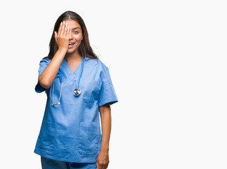 Young arab doctor surgeon woman over isolated background covering one eye with hand with confident smile on face and surprise emotion.