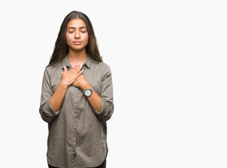 Young beautiful arab woman over isolated background smiling with hands on chest with closed eyes and grateful gesture on face. Health concept.