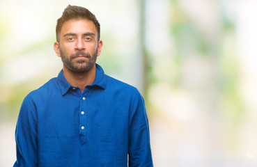 Adult hispanic man over isolated background with serious expression on face. Simple and natural looking at the camera.