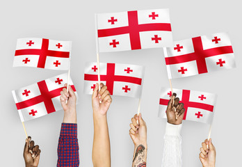 Hands waving flags of Georgia