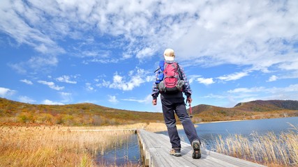 秋空と紅葉の草原を歩く