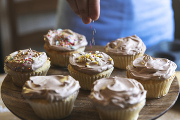 Hand adding sprinkles to chocolate cupcake food photography recipe idea
