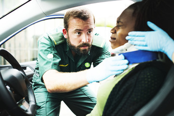 Paramedic placing a cervical collar to an injured woman from car accident