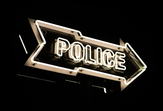 Bright White Neon Sign Points Towards Police Station Dark Night
