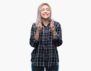 Young blonde woman over isolated background smiling crossing fingers with hope and eyes closed. Luck and superstitious concept.