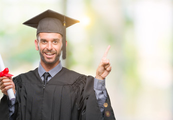 Young handsome graduated man holding degree over isolated background very happy pointing with hand and finger to the side