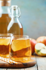 Organic Apple cider or juice on a wooden table with copy space. Two glasses with drink and autumn...