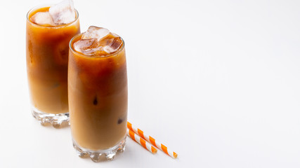 Ice coffee in a tall glass with cream poured over and coffee beans. Cold summer drink on white...