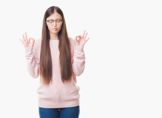 Fototapeta na wymiar Young Chinese woman over isolated background wearing glasses relax and smiling with eyes closed doing meditation gesture with fingers. Yoga concept.