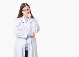 Young Chinese doctor woman over isolated background with hand on chin thinking about question, pensive expression. Smiling with thoughtful face. Doubt concept.