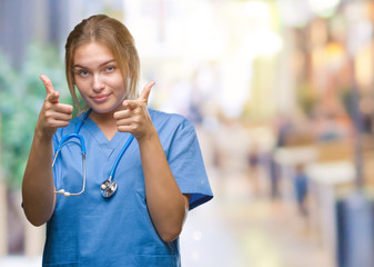 Young caucasian doctor woman wearing surgeon uniform over isolated background pointing fingers to camera with happy and funny face. Good energy and vibes.