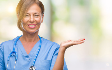 Middle age senior nurse doctor woman over isolated background smiling cheerful presenting and pointing with palm of hand looking at the camera.