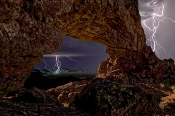A lightning storm viewed from the arch on the top of Eagle Eye Mountain near Aguila Arizona. The colors were achieved through HDR toning.