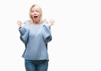 Young beautiful blonde woman wearing winter sweater over isolated background celebrating crazy and amazed for success with arms raised and open eyes screaming excited. Winner concept