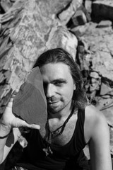 Portrait of a man among the stones. In the hands of a huge stone, covers the floor of the face.