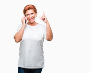 Obraz na płótnie Canvas Atrractive senior caucasian redhead woman talking on smartphone over isolated background surprised with an idea or question pointing finger with happy face, number one