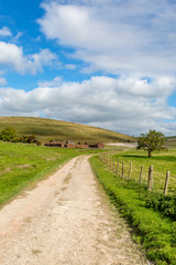 Obraz premium A country path leading to disused farm buildings