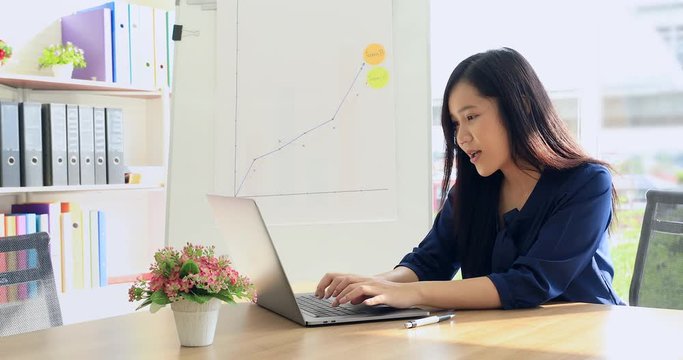 Young and beautiful Asian woman with Orthodontic brackets sitting in room and typing on keyboard of laptop computer.
