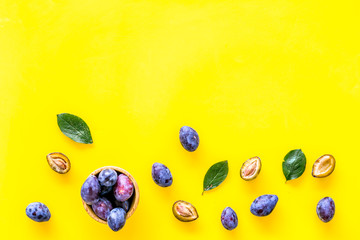 Blue plum for dessert. Purple plum and leaves pattern on yellow background top view copy space